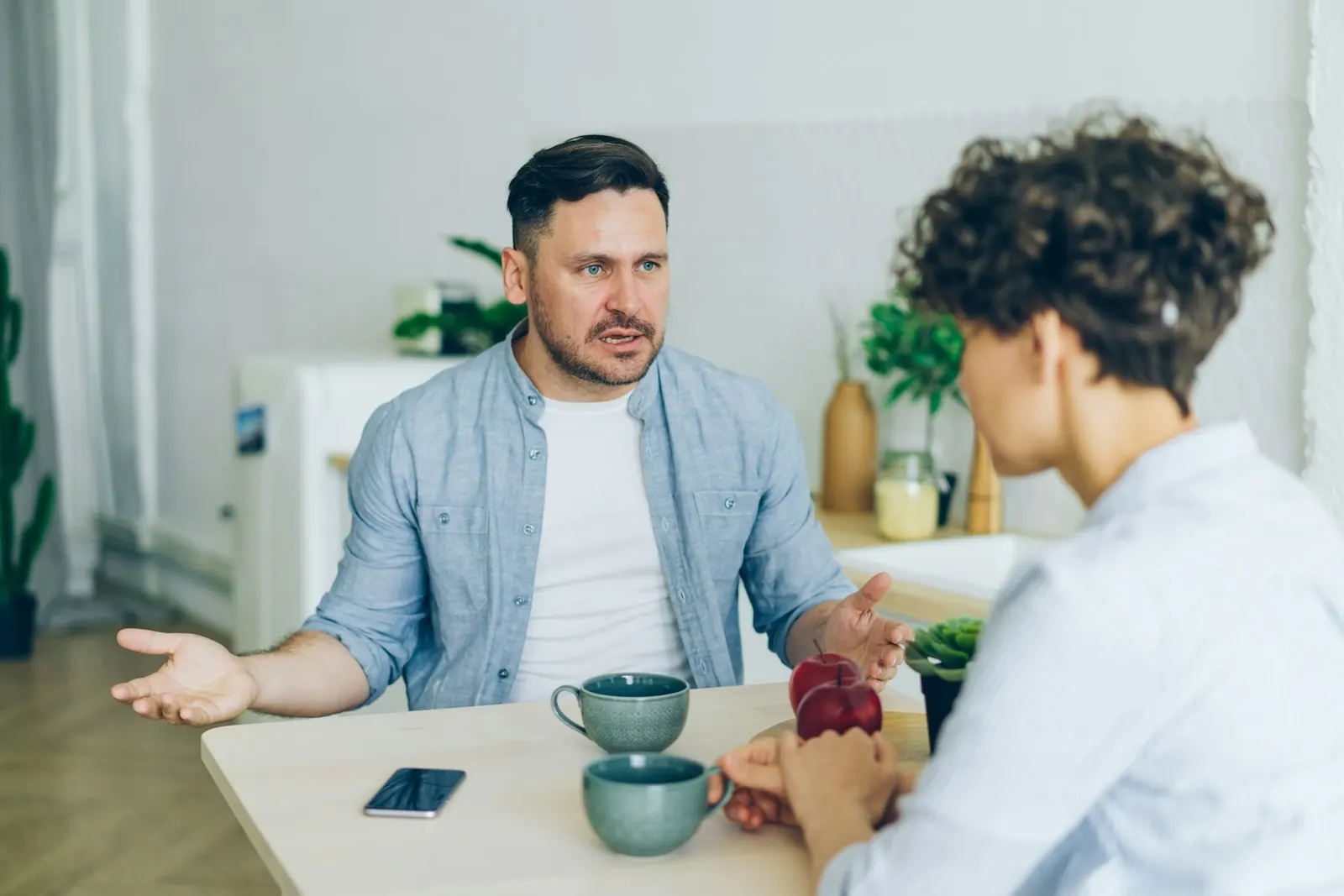Man and woman in a heartfelt conversation over coffee at a table