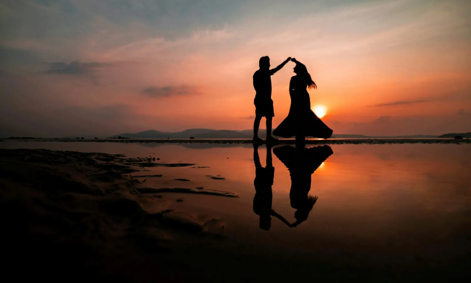 Silhouetted couple dancing on the beach at sunset