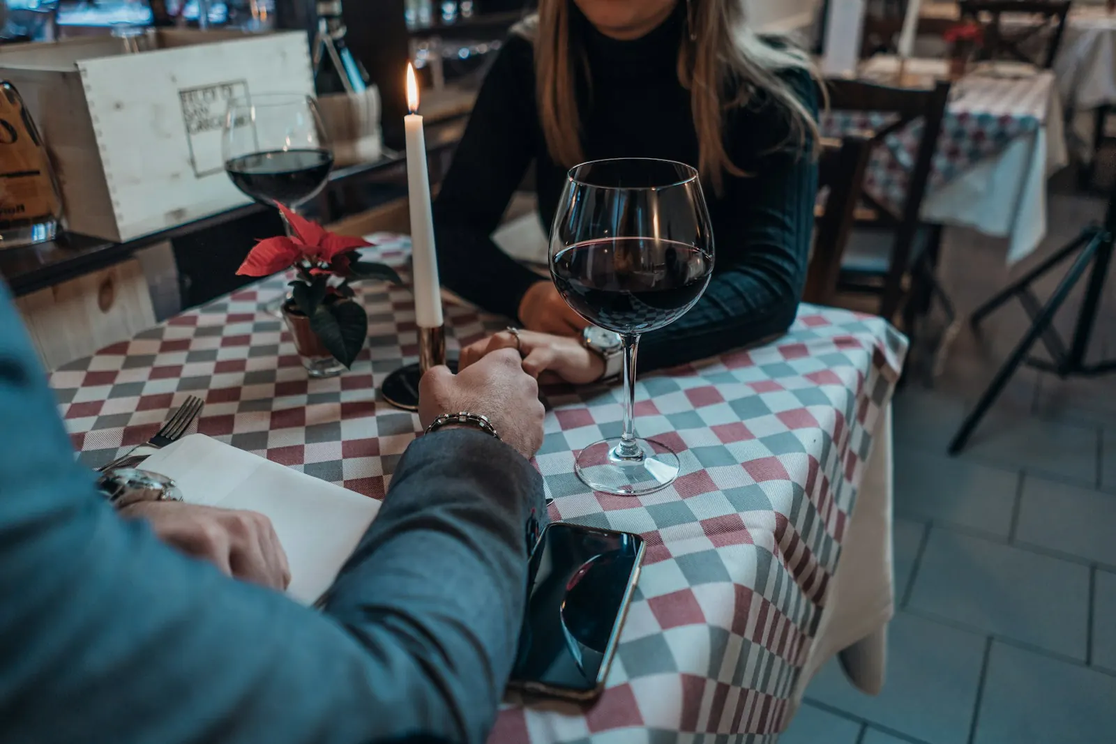 Couple holding hands over a candlelit restaurant table with wine