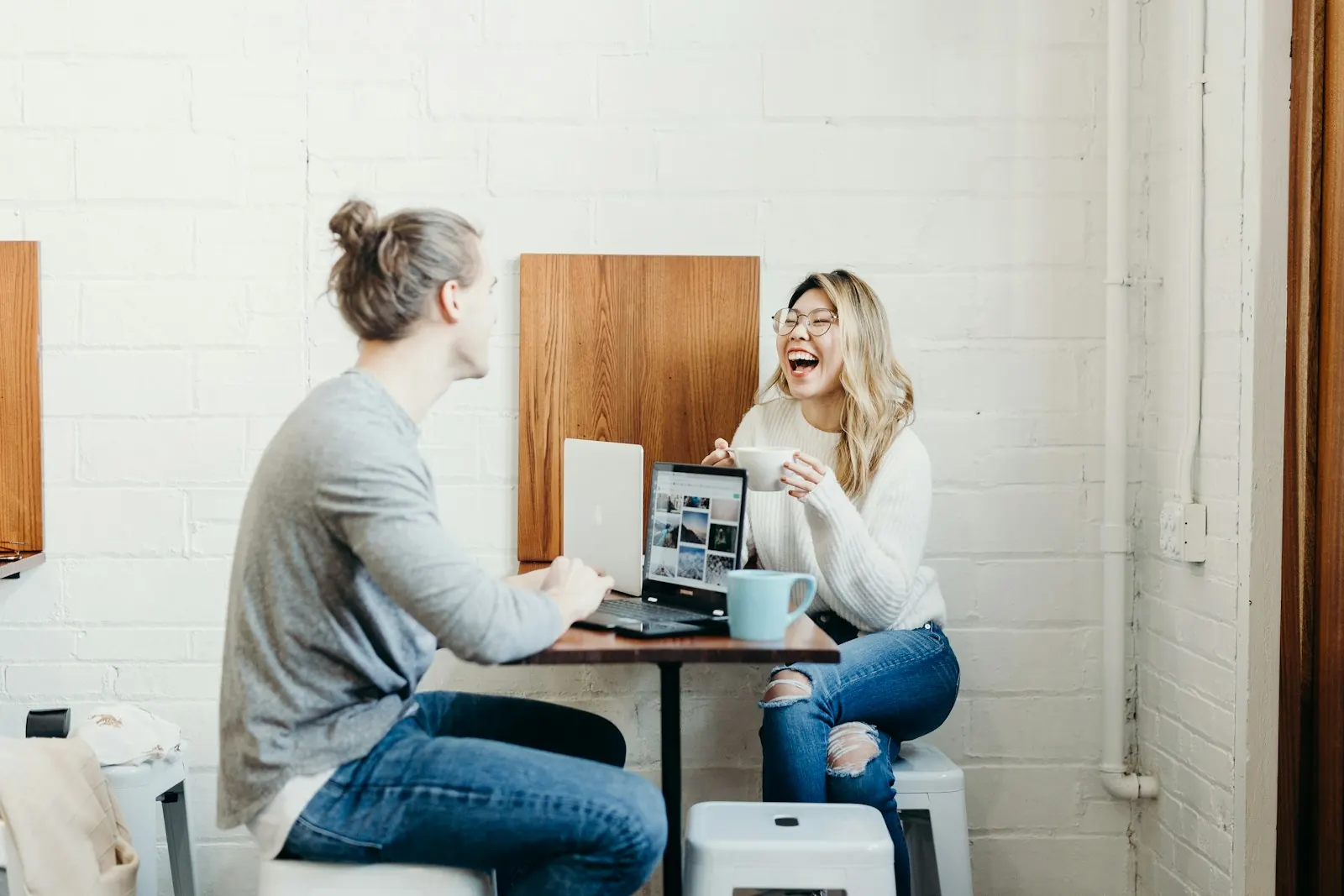 Couple laughing together at a table in a bright cafe