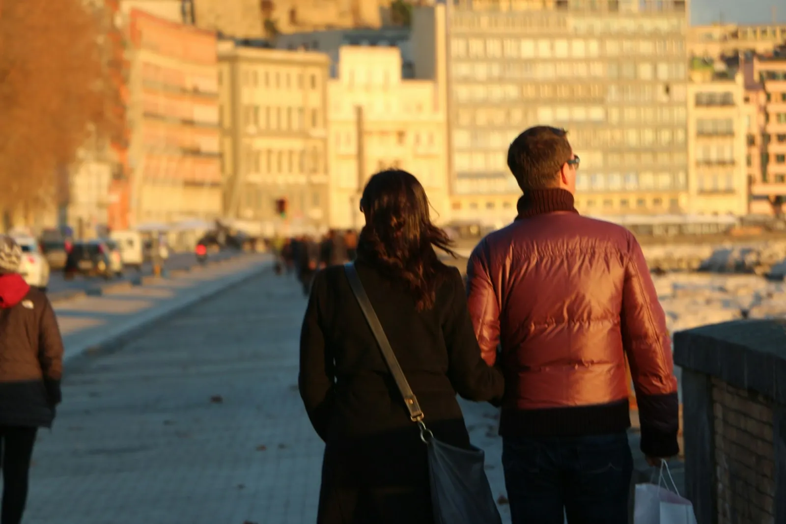 Couple walking along a city waterfront at golden hour