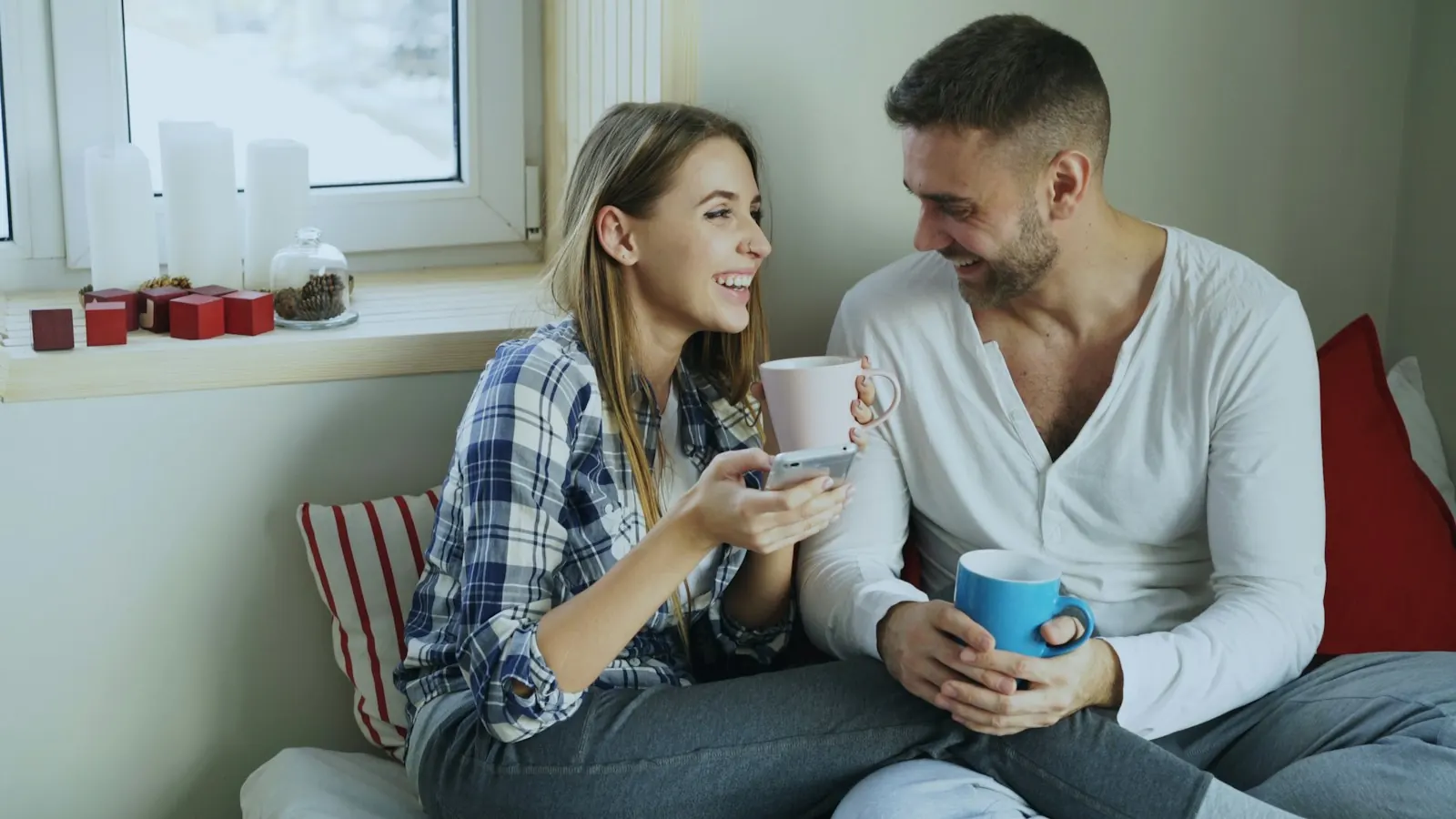 Smiling couple sharing coffee by a window