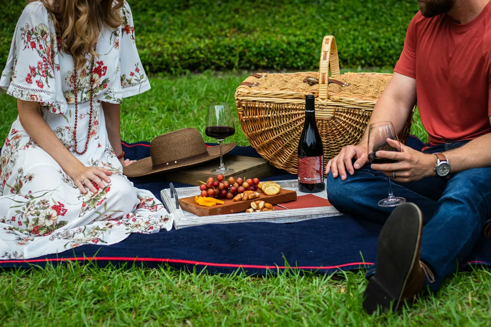 Couple on a picnic blanket with a basket, wine and snacks