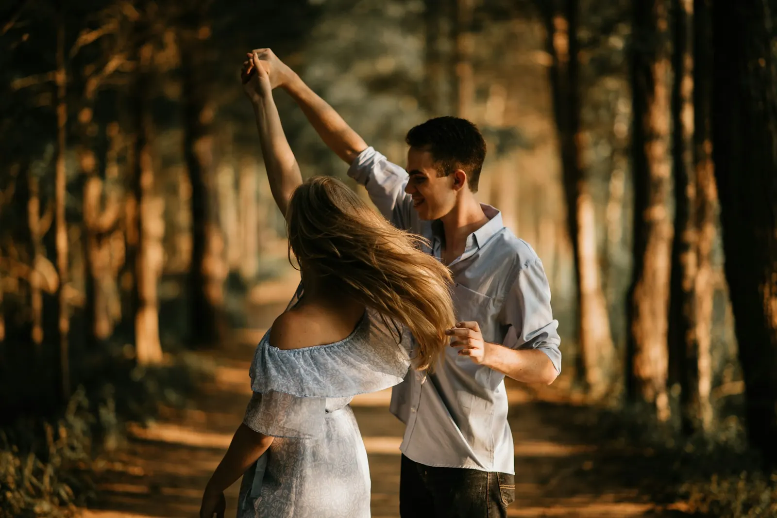 Couple dancing together on a sunlit forest path