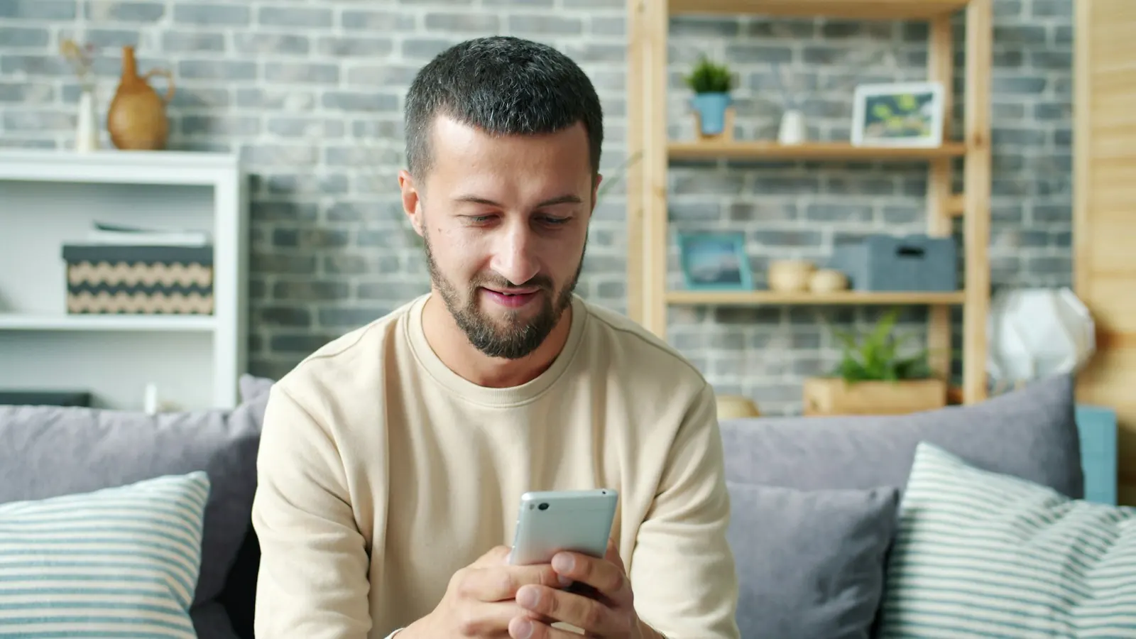 Man smiling while looking at his phone on a couch