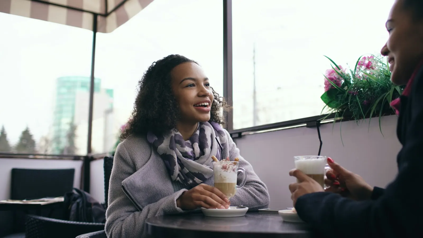 Woman smiling across a cafe table at someone over coffee