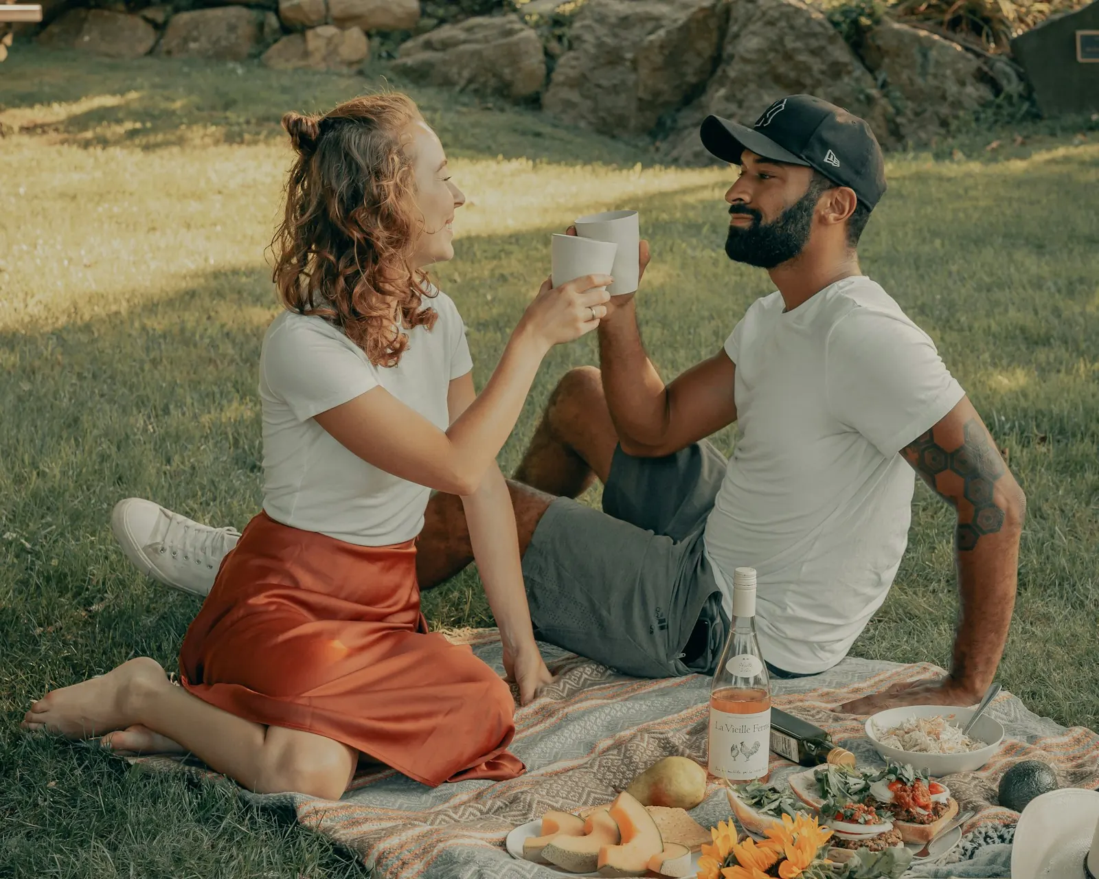 Couple talking and sharing a toast on a picnic blanket