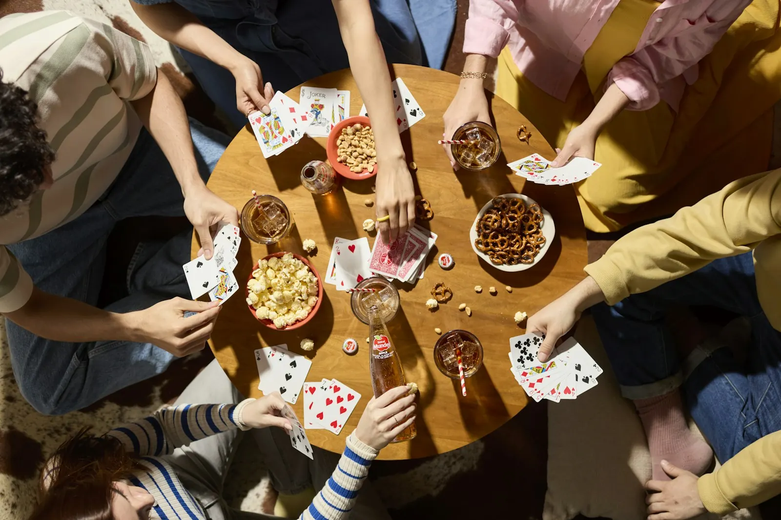 Friends playing cards around a table with snacks and drinks