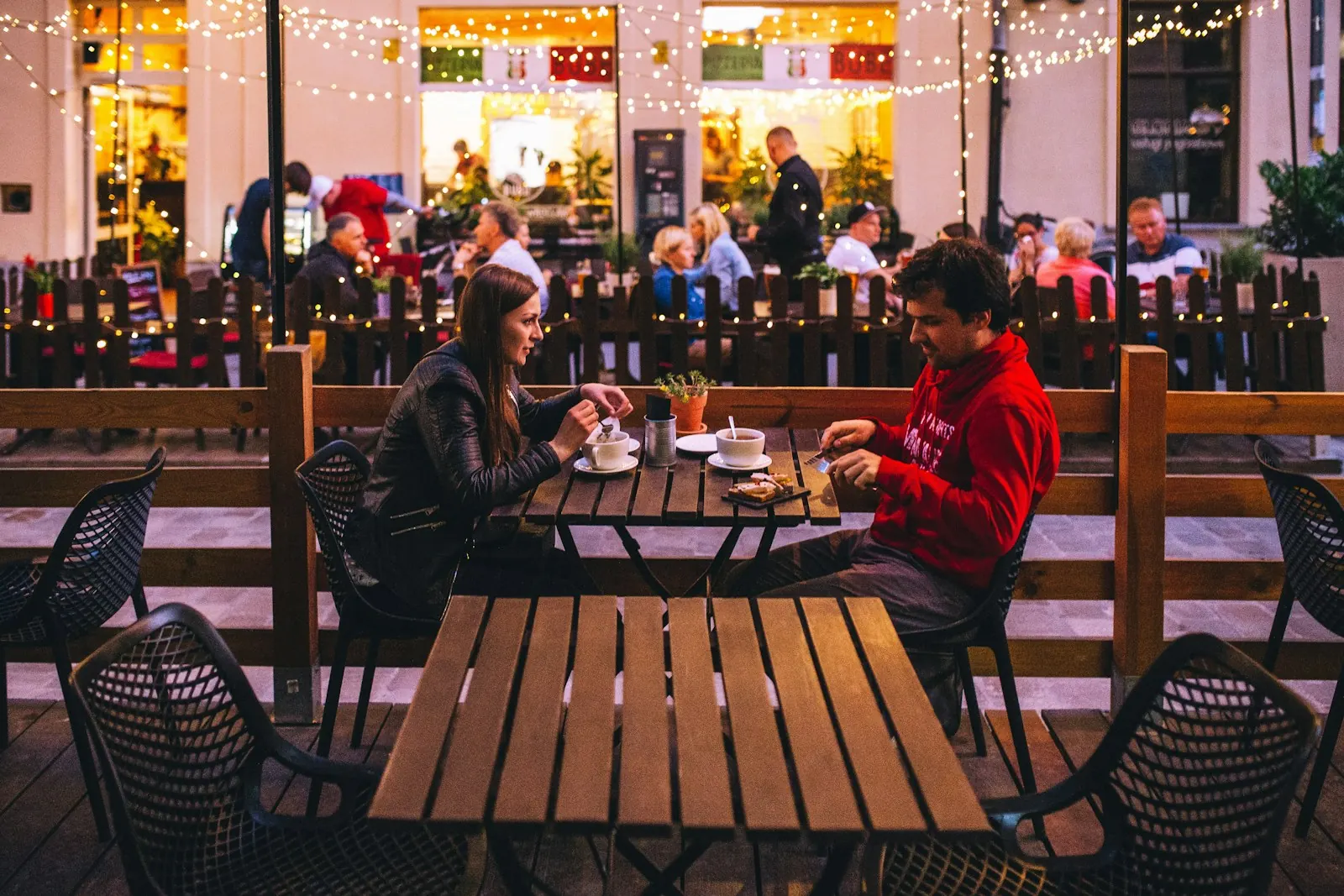Couple talking over dinner on a lantern-lit restaurant terrace