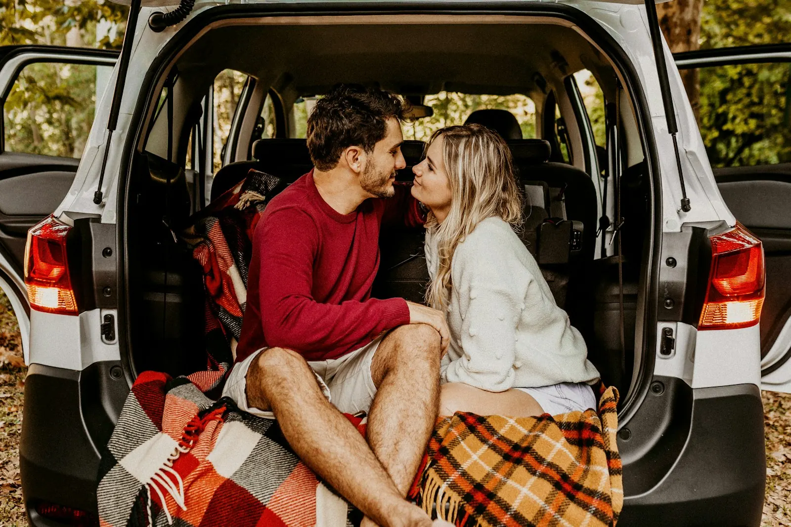 Couple sitting in the open back of a car on a road trip