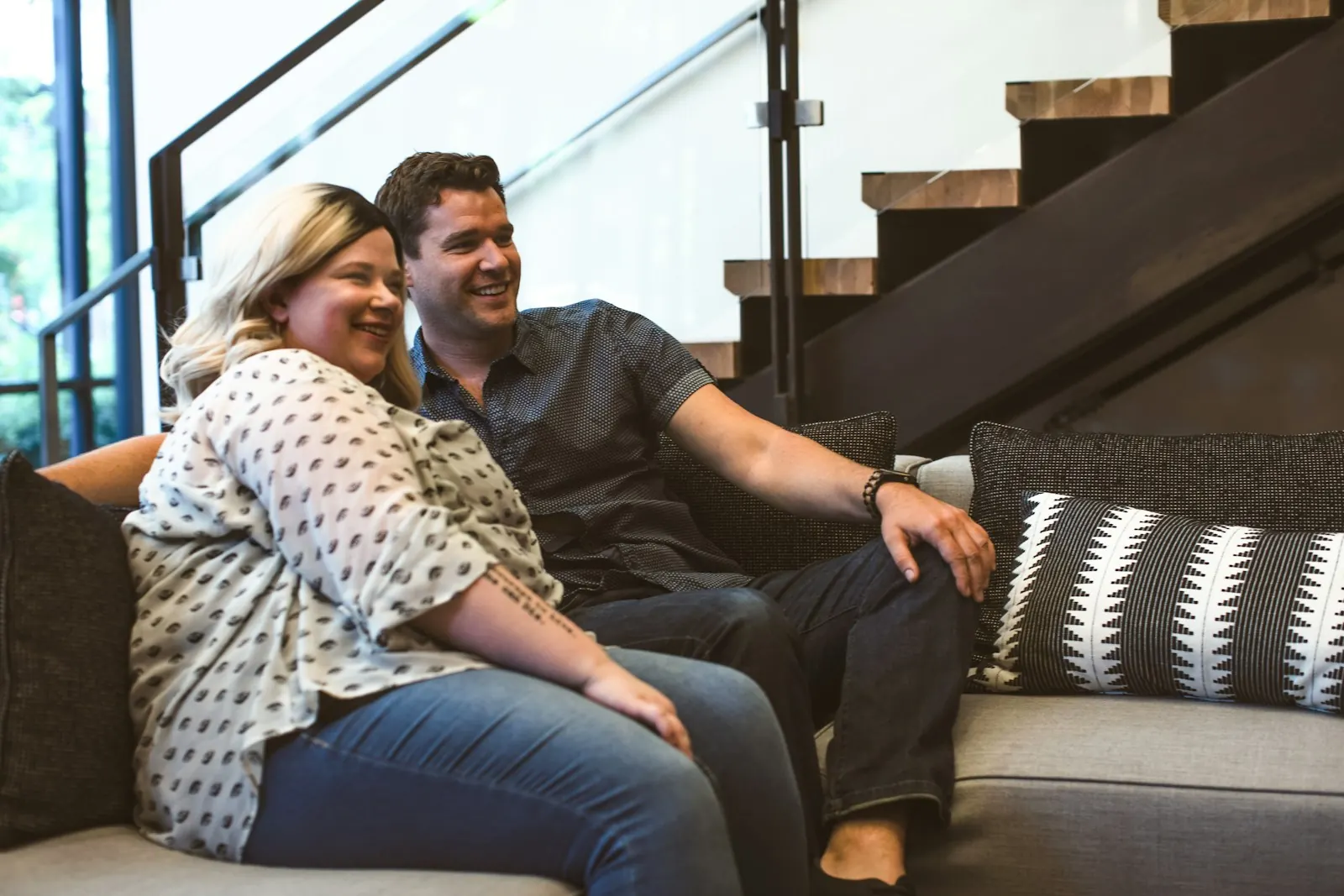 Couple laughing together on a sofa at home