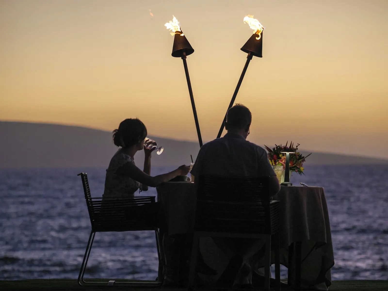 Couple enjoying a sunset anniversary dinner by the sea